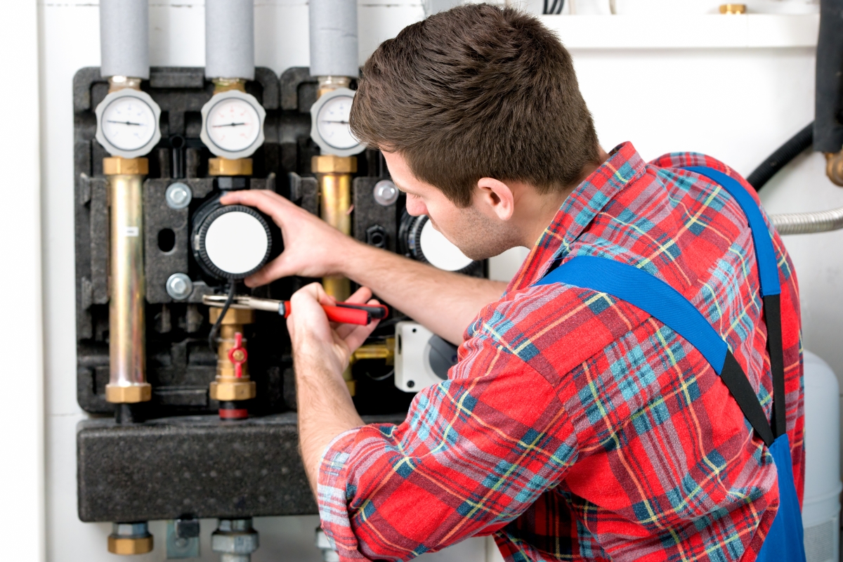 man in plaid shirt and overalls working on gas pipes