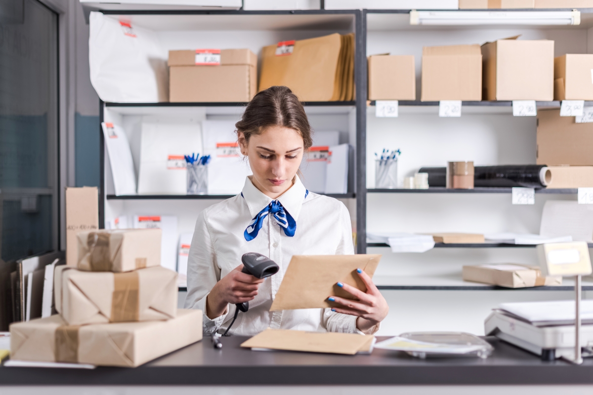 person standing in a mailroom, scanning an envelope