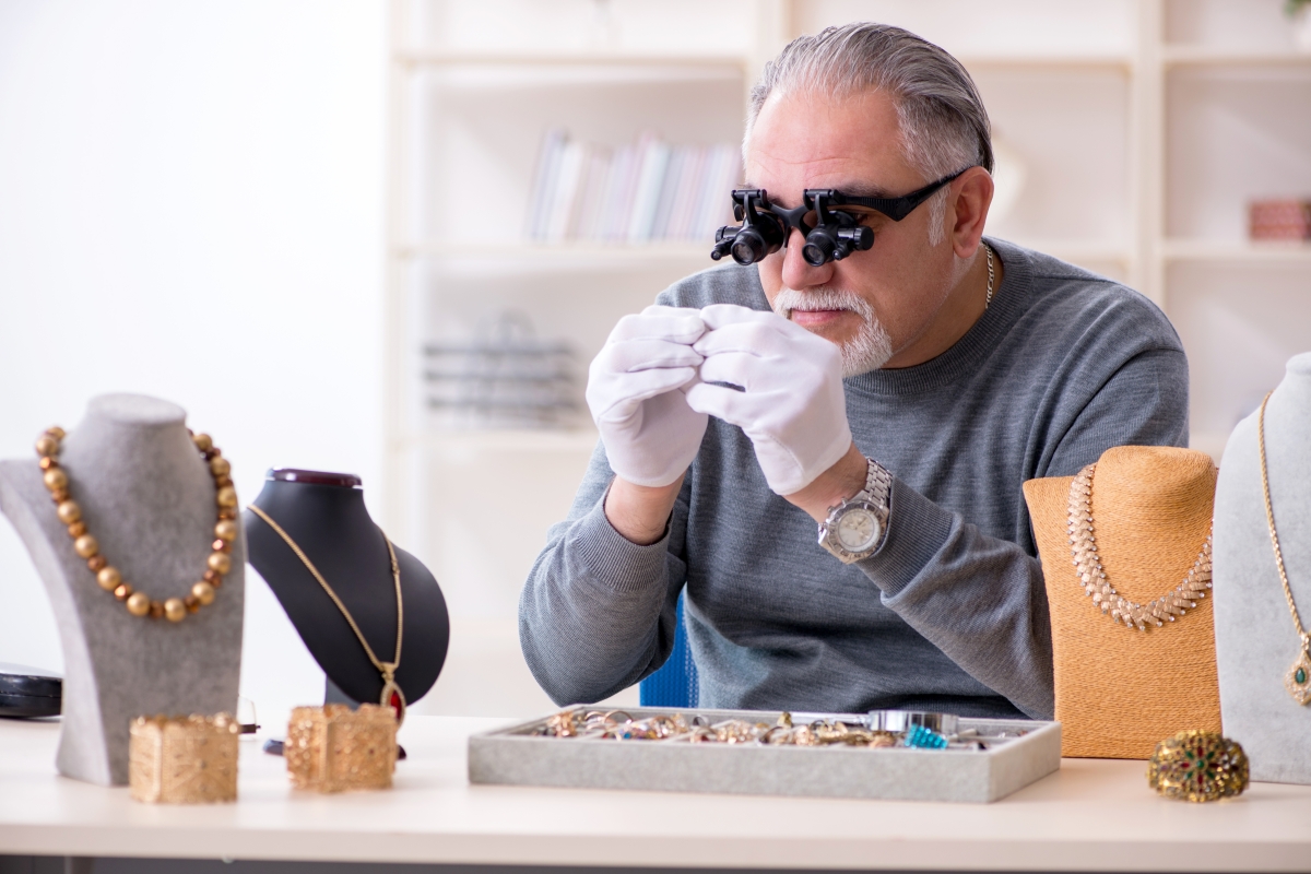 man wearing white gloves and special eyewear while inspecting jewelry