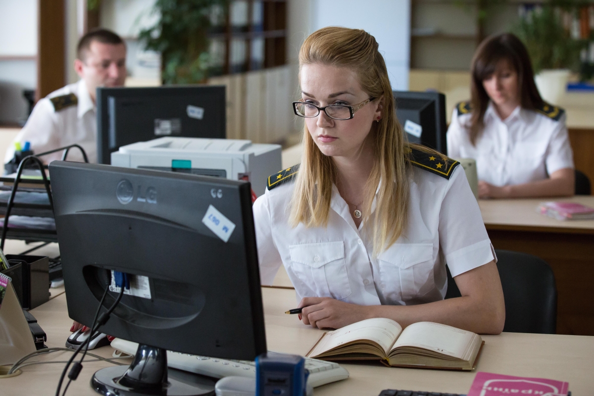 people, wearing a white uniform shirt, sitting in an office working on computers
