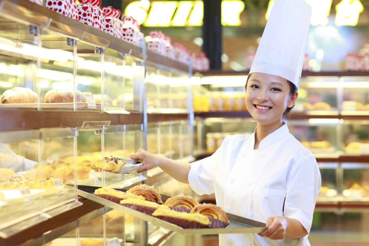 baker stocking shelves with pastries in a bakery