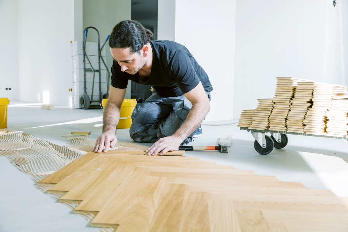 worker kneeling and measuring while laying flooring