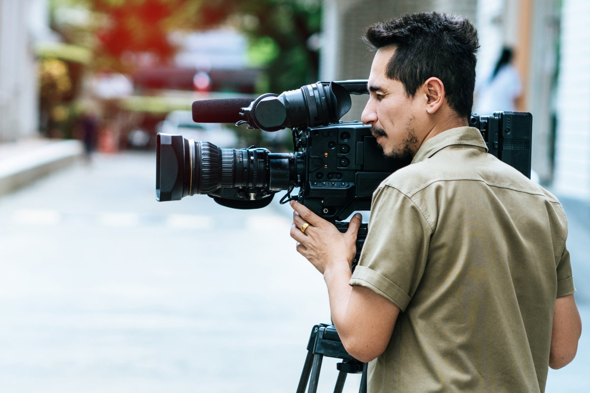 man operating a professional video camera outside
