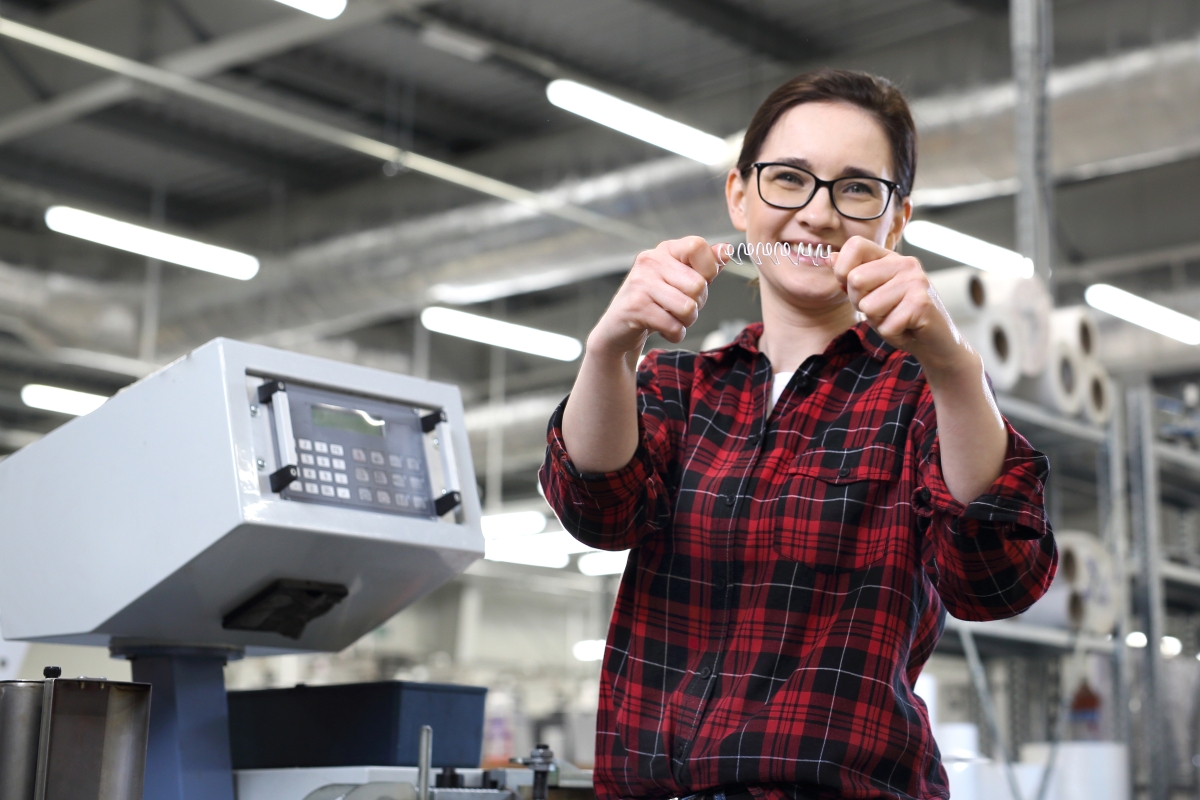 person holding up a spiral binding coil in an industrial setting