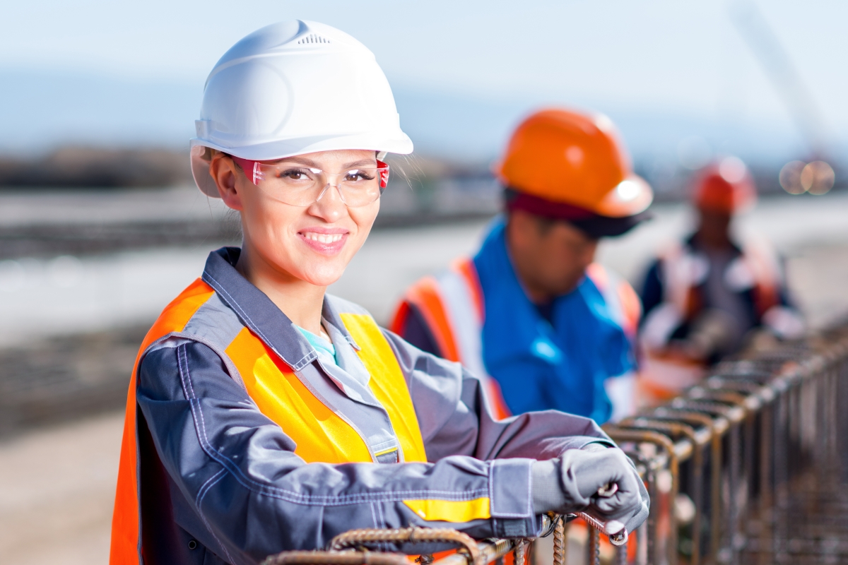 woman wearing safety glasses and a hard hat at an industrial site