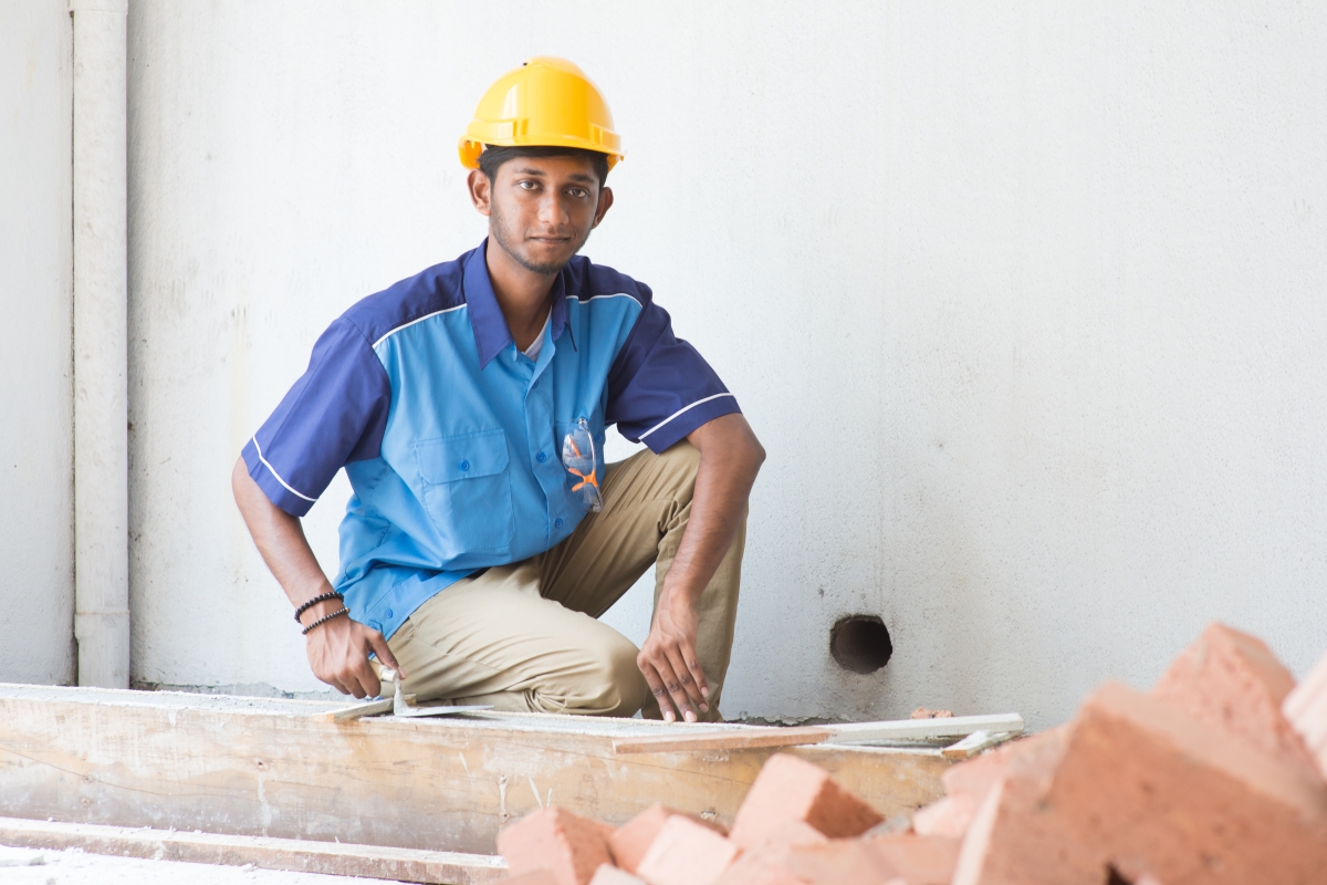 bipoc male crouched with a trowel and bricks