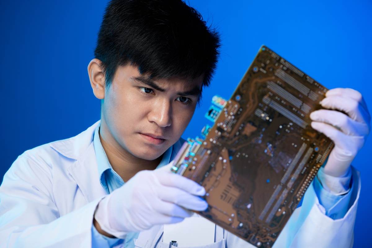 person holding up and looking at a circuit board