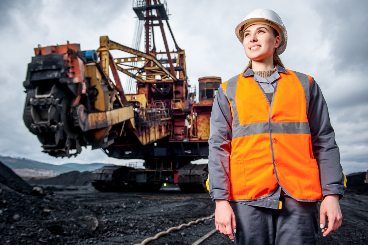 young woman wearing safety vest and hard hat at a mining site