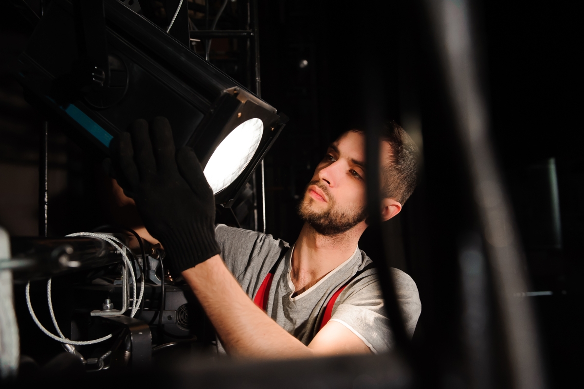 man adjusting a stage lighting fixture