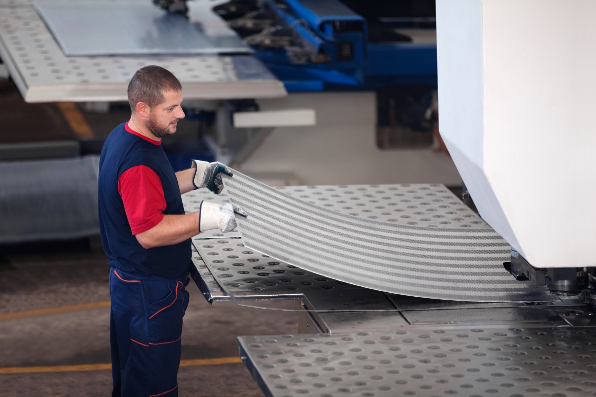 person running sheet metal through a machine in a warehouse