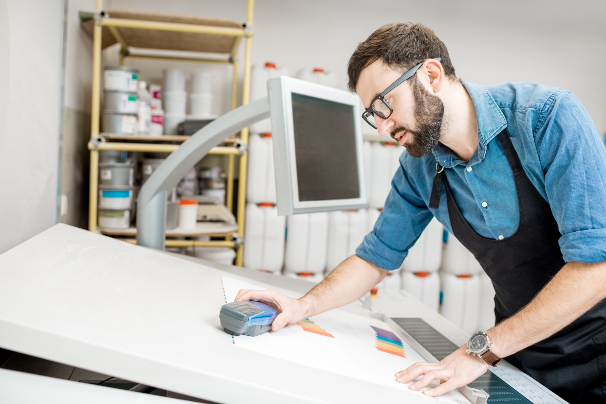 person leaning over a drafting table looking at a sheet of paper
