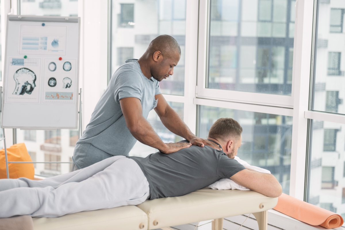 man giving a patient a massage as the patient is lying face down on a massage table
