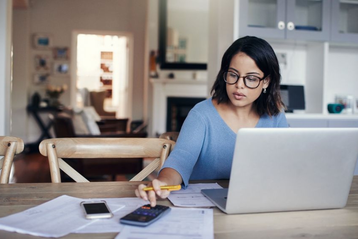 woman using a calculator at kitchen table