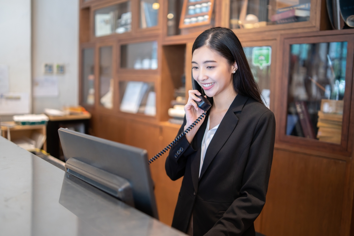 woman on the phone while looking at a computer behind a desk