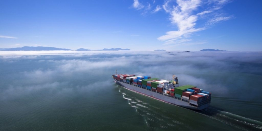 Large cargo ship sailing on ocean with blue skies