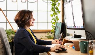 female working on computer near a window