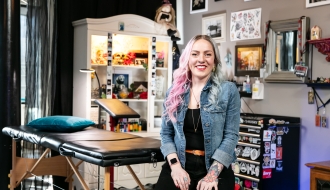 Smiling female tattoo artist sitting in a tattoo shop